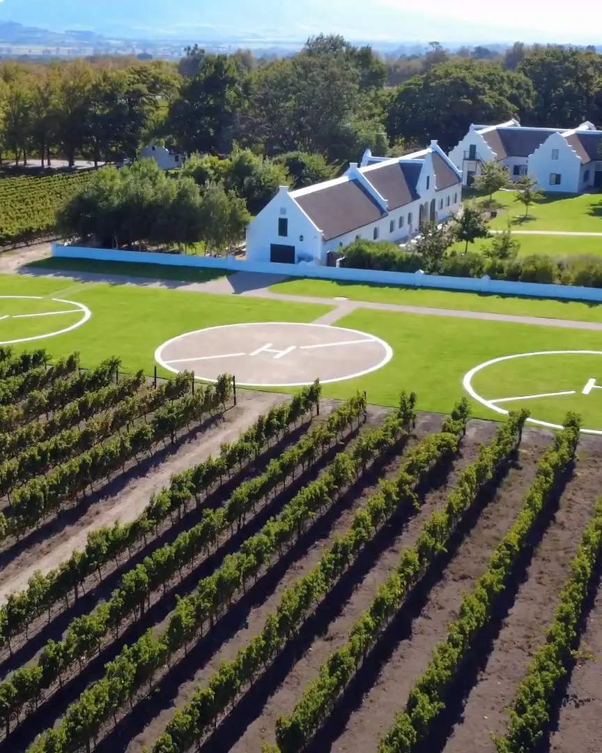 Luftaufnahme einer privaten Lodge im kapholländischen Stil zwischen Weinbergen bei Kapstadt